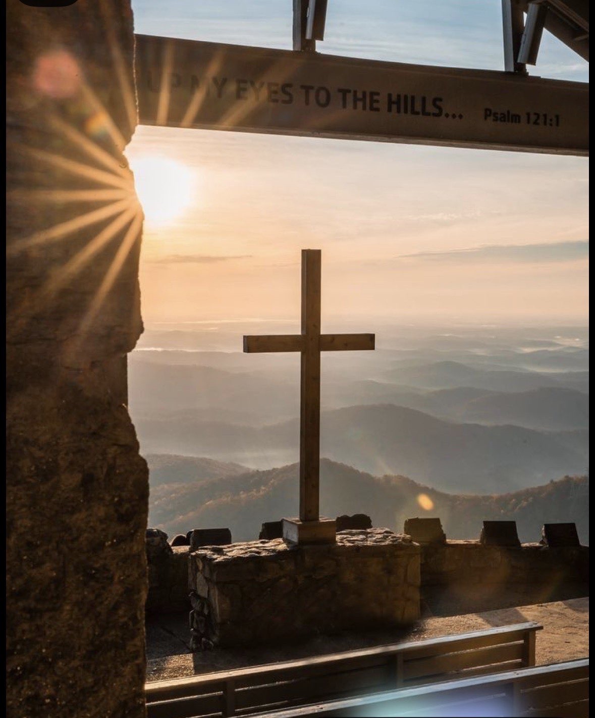 A mountain view with a cross at sunset