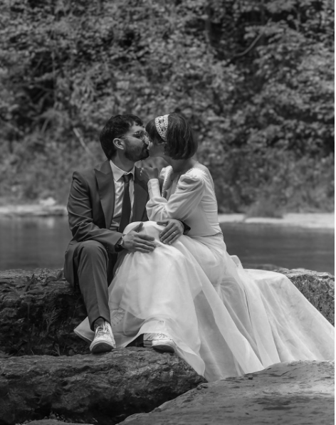 Charlie and Samuel seated together on rocks in their wedding attire